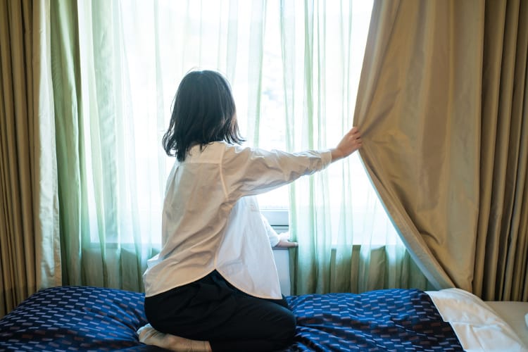 Woman drawing curtain next to bed before sleeping