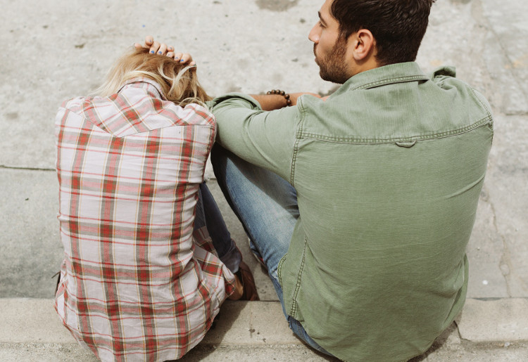 Man sitting next to despondent woman on a curb